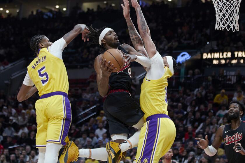 Portland Trail Blazers forward Jerami Grant, center, shoots between Los Angeles Lakers forward Cam Reddish, left, and forward Anthony Davis during the second half of an NBA basketball In-Season Tournament game in Portland, Ore., Friday, Nov. 17, 2023. (AP Photo/Craig Mitchelldyer)
