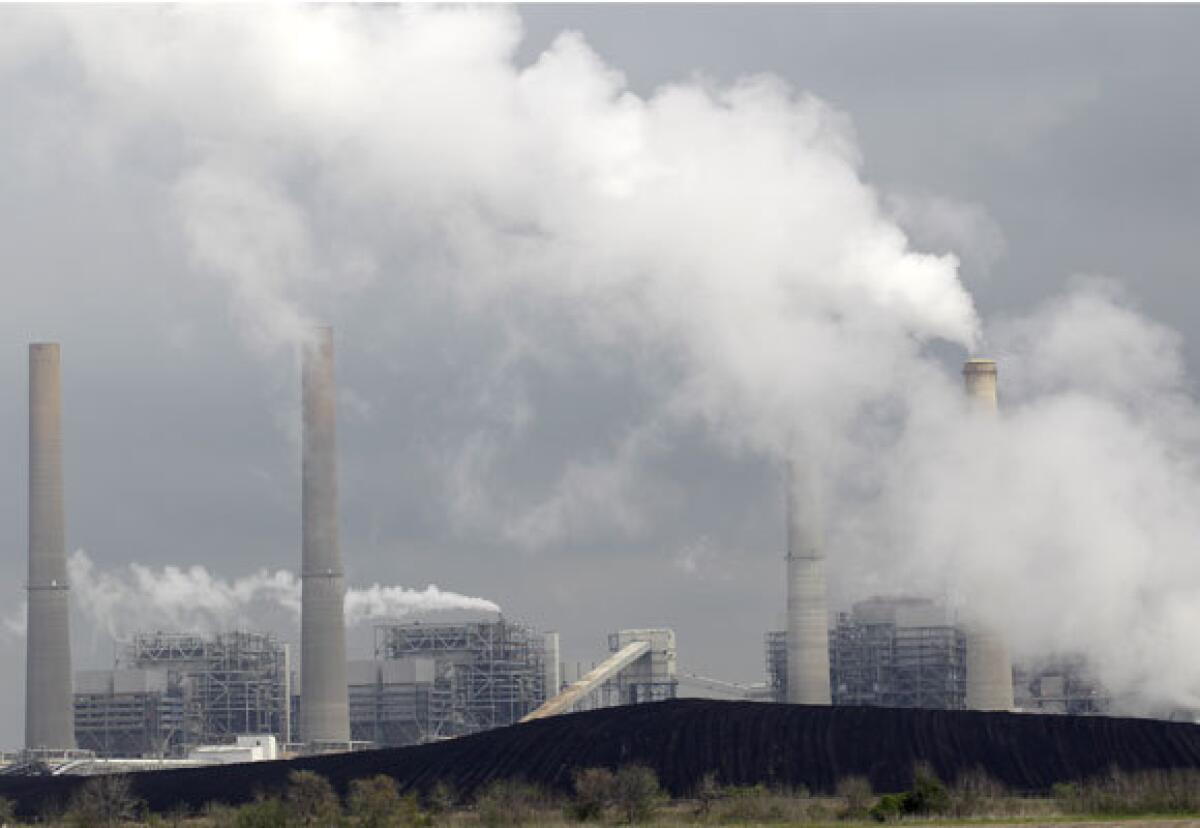 Exhaust rises from smokestacks in front of piles of coal at NRG Energy's W.A. Parish Electric Generating Station in Texas in 2011. The Environmental Protection Agency proposed new rules Thursday that would lower the amount of fine particulate matter, or soot, that enters the air from sources such as power plants and diesel engines.