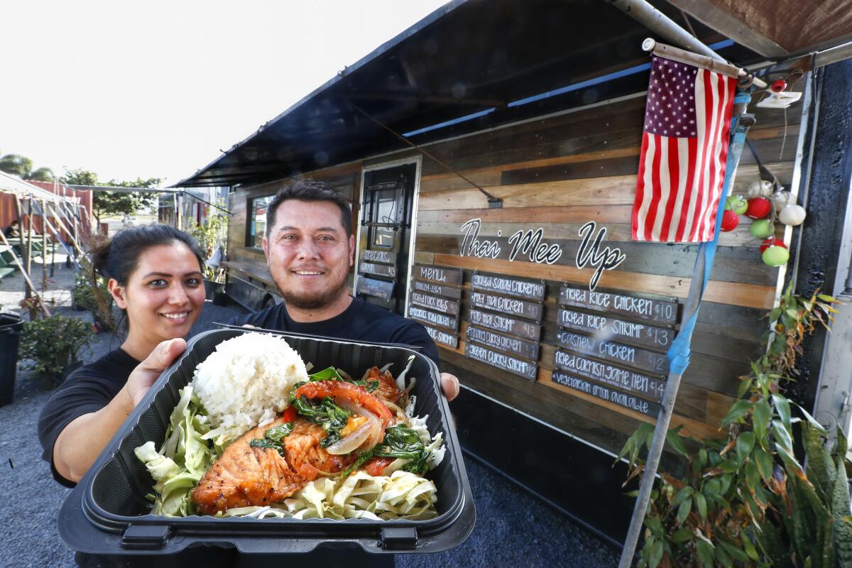 Brandie and Tom Sribura, co-owners of Thai Mee Up in Kahului, Hawaii, hold a salmon plate with rice and broccoli.