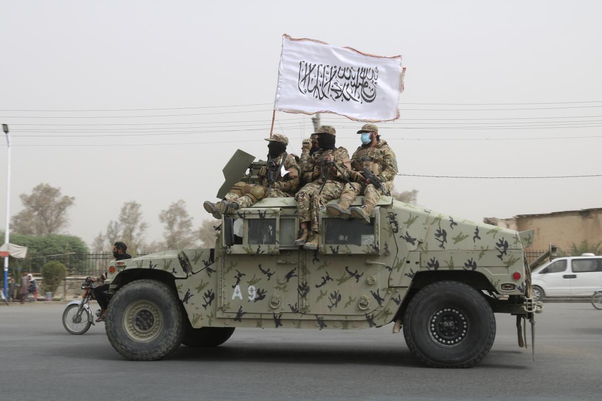 Taliban fighters waving flag from patrol vehicle