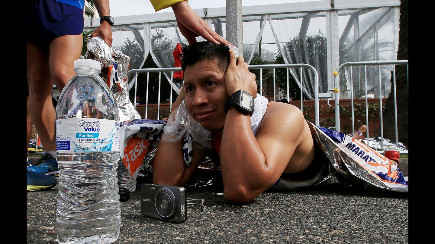 Marathon runner Ronnie Sanchez rests on the road at the finish line.