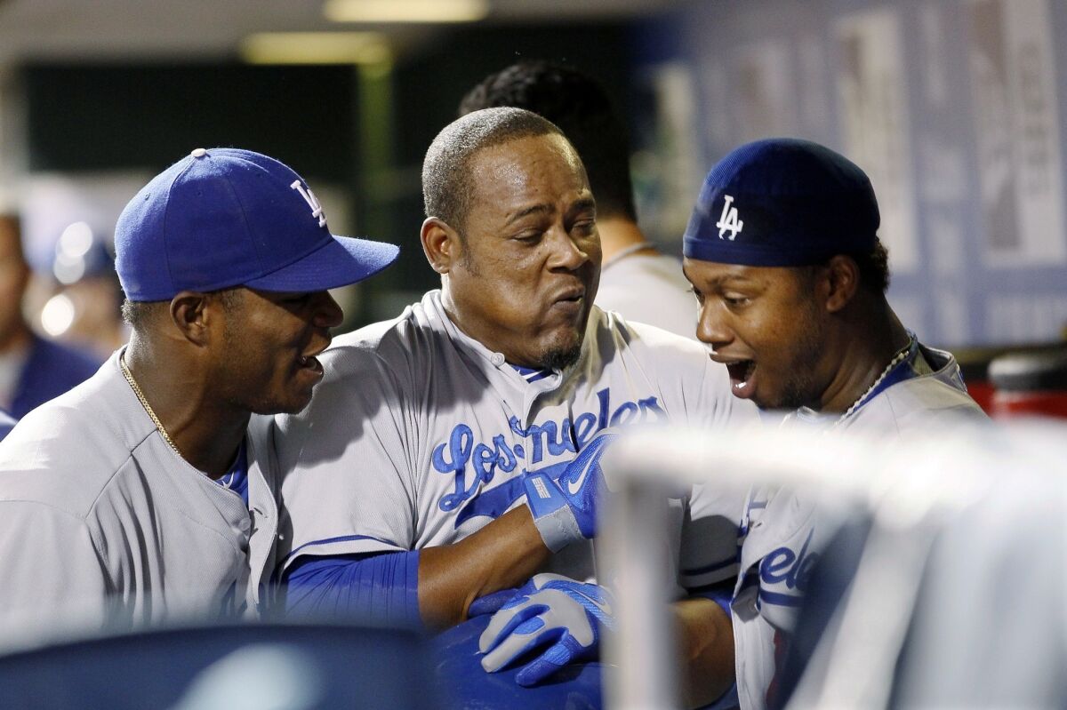 Yasiel Puig, left, Juan Uribe and Hanley Ramirez celebrate in the dugout after Uribe's three-run homer in the ninth inning against the Philadelphia Phillies on Saturday.
