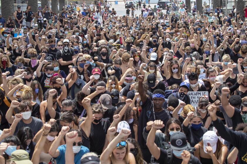 HERMOSA BEACH, CA - JUNE 02: Several hundred Black Lives Matter protesters take a knee and hold their fists in the air during a moment of silence to honor George Floyd during a peaceful protest march from Manhattan Beach to Hermosa Beach and return at the Hermosa Beach Pier Plaza Tuesday, June 2, 2020. (Allen J. Schaben / Los Angeles Times)