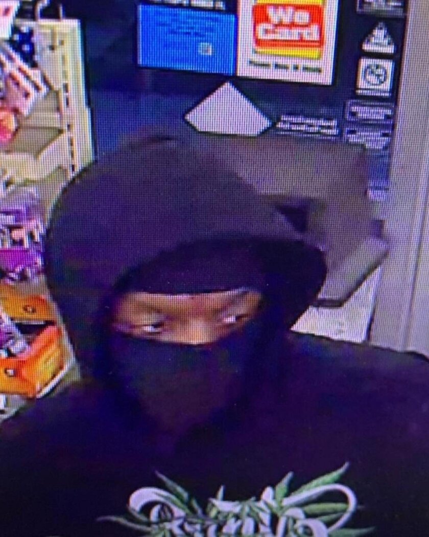A man in a black hoodie and a black mask in a surveillance image inside a convenience store
