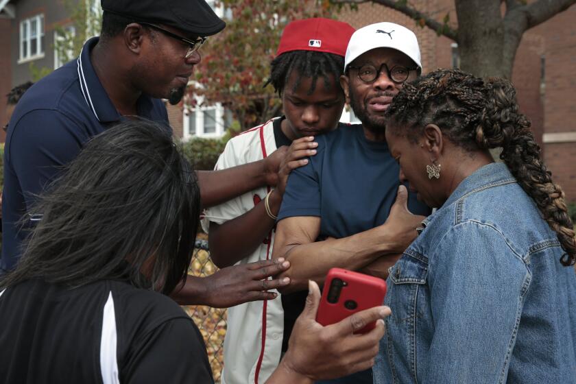Messiah Miller, 16, center, a junior at Central Visual & Performing Arts High School, prays with his teacher Ray Parks, second from right, following a shooting at the school on Monday, Oct. 24, 2022, in the Southwest Garden neighborhood. "He looked at me, he pointed the gun at me," said Parks, a dance teacher, who came face to face with the gunman. (Robert Cohen/St. Louis Post-Dispatch via AP)
