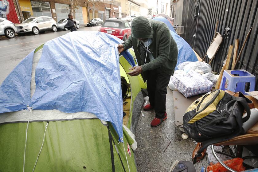 LOS ANGELES, CA - NOVEMBER 20, 2019 John Gunn looks at his tent in Skid Row where his belongings were soaked as rain and hail fall in downtown Los Angeles Wednesday November 20, 2019 after a weekend of record-breaking high temperatures. Angelenos broke out their jackets and umbrellas for the first measurable moisture in several months. (Al Seib / Los Angeles Times)