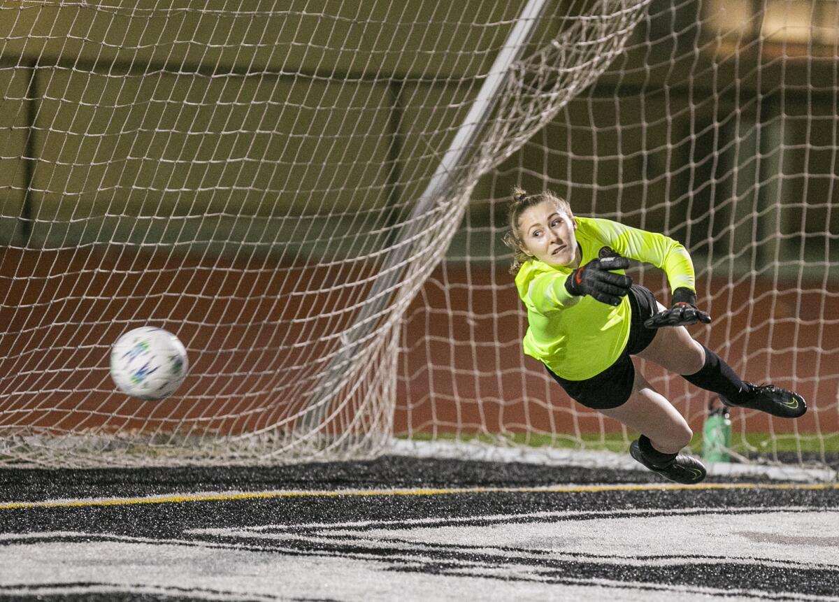 Huntington Beach's Reese Doyle makes a diving save on a shot on goal during a Surf League match against Edison on Tuesday.