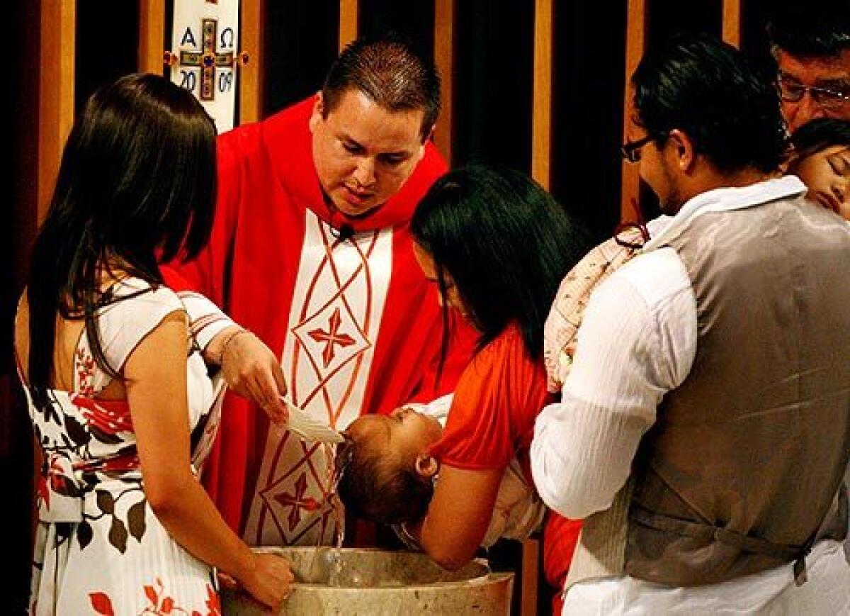 Father Erik Esparza baptizes a baby at St. Joseph Catholic Church in Barstow. He is one of only two priests at his parish, serving 1,200 families.