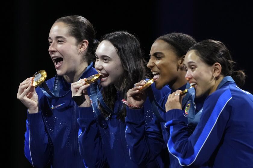 El equipo femenino estadounidense de esgrima compuesto por Lee Kiefer, Lauren Scruggs, Jaqueline Dubrovich y Maia mei Weintraub celebra en el podio al conquistar la medalla de oro en el florete por equipos en los Juegos Olímpicos el jueves 1 de agosto del 2024. (AP Foto/Andrew Medichini)