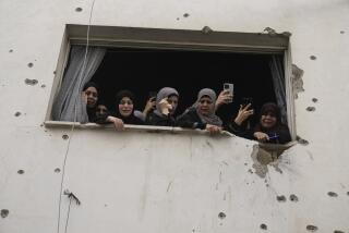 Mourners watch the funeral of Palestinian men who were killed during an Israeli military operation, from a building damaged with bullet holes, in Jenin, West Bank, Friday, Sept. 6, 2024. (AP Photo/Majdi Mohammed)