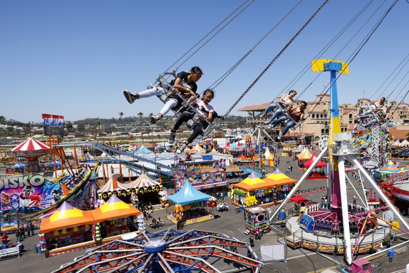 San Diego, CA - June 12: Maya Mendoza, left, and her sister Maizie ride the Sky Flyer swing ride on the opening day of the San Diego County Fair on Wednesday, June 12, 2024. (K.C. Alfred / The San Diego Union-Tribune)