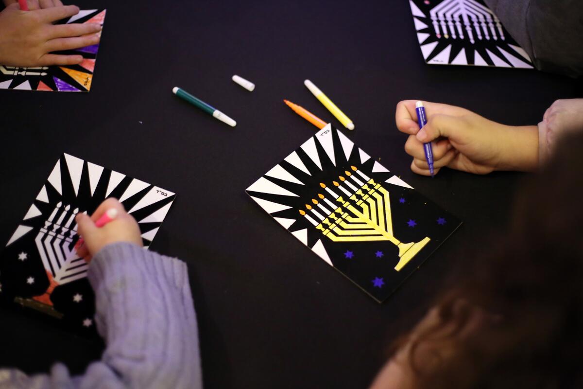 Children color a menorah for arts and crafts during Festival of Lights public menorah lighting.