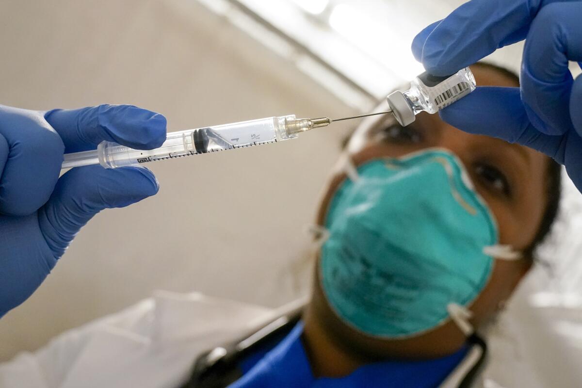 A close-up of gloved hands holding a syringe 