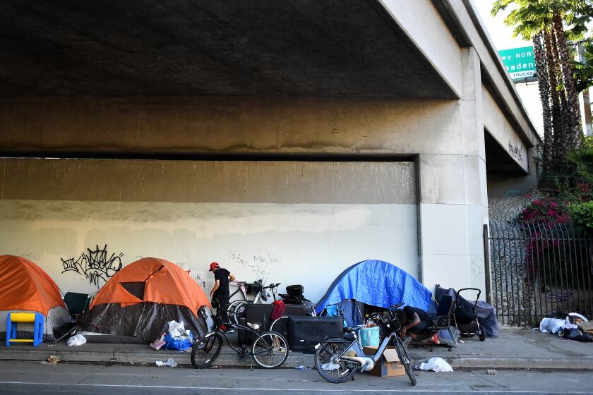 LOS ANGELES, CALIFORNIA MAY 19, 2020-Homeless people line up tents along Figueroa St. under the 101 Freeway in Downtown Los Angeles Tuesday. Thousands of homeless people living near freeways in L.A. County are in line to receive alternative shelter during the COVID-19 pandemic. (Wally Skalij/Los Angeles Times)