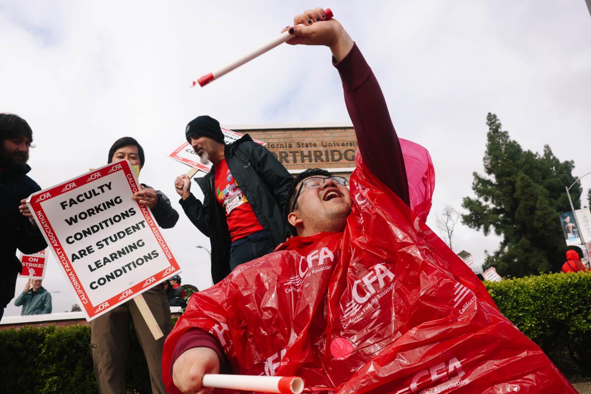 Cal State University faculty member in red poncho carry picket signs.