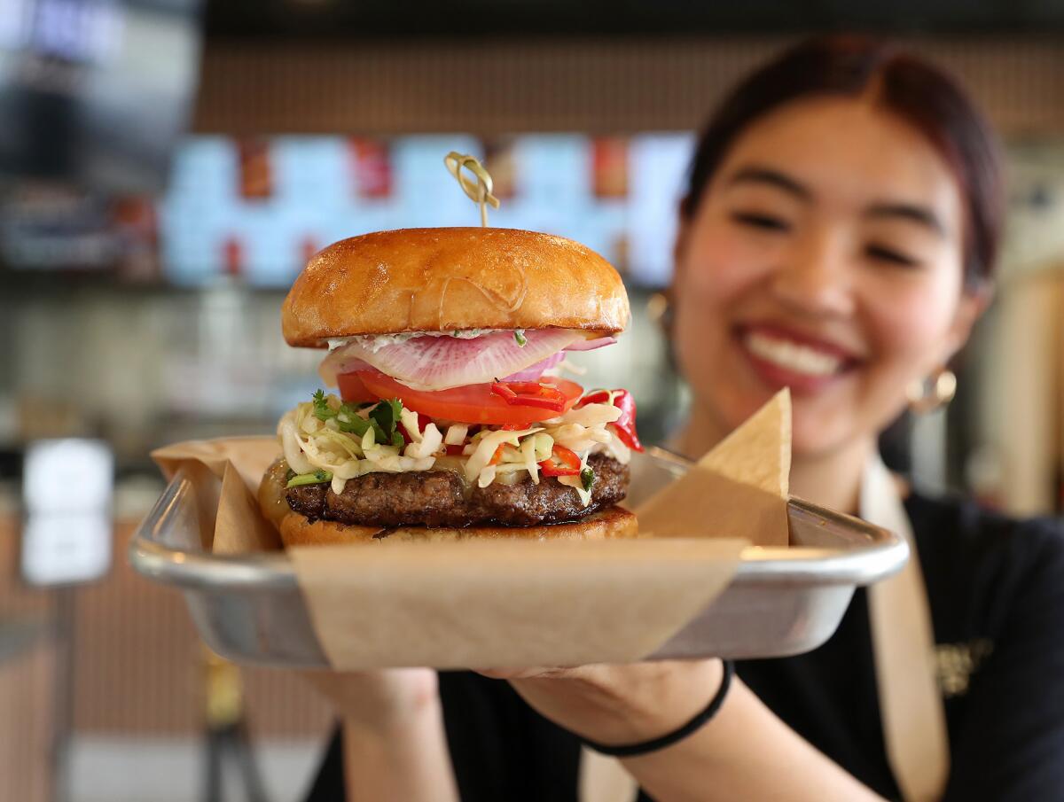Emme Do holds up a Roadside burger at Burns Road in Tustin, made with grass-fed Halal beef, spiced like slow cooked nihari.