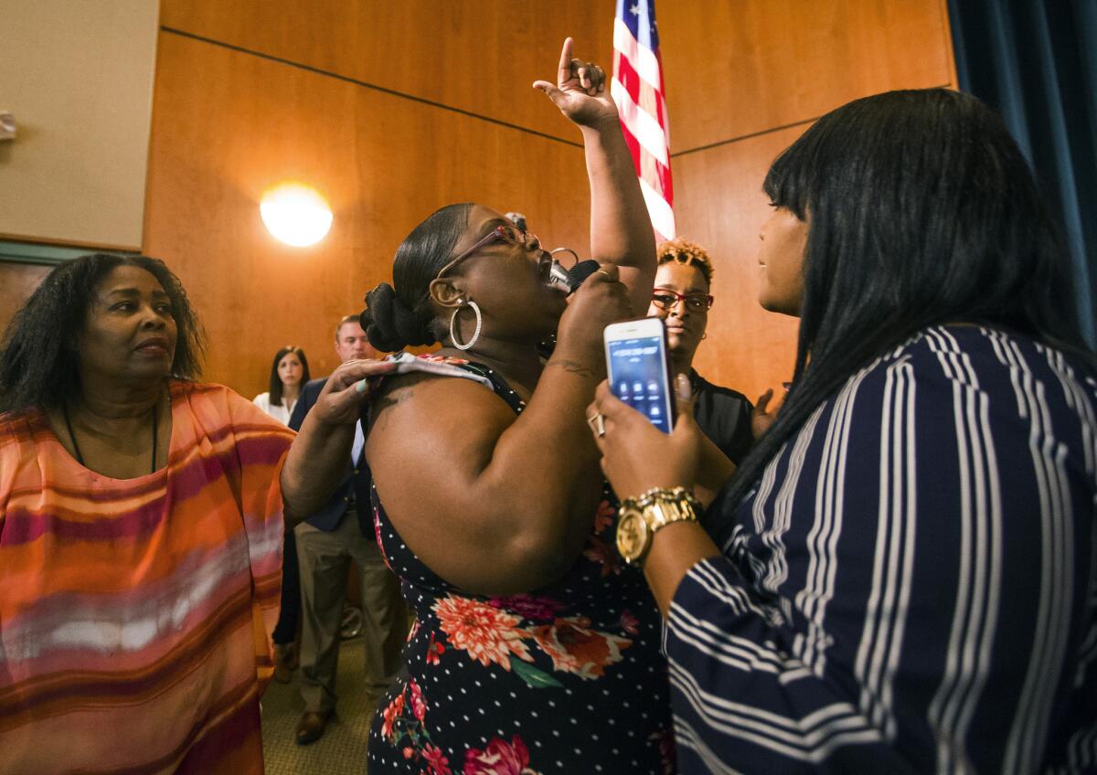 Komaneach Wheeler is restrained by family as she yells at Democratic presidential candidate and South Bend Mayor Pete Buttigieg during a town hall Sunday in South Bend, Ind.