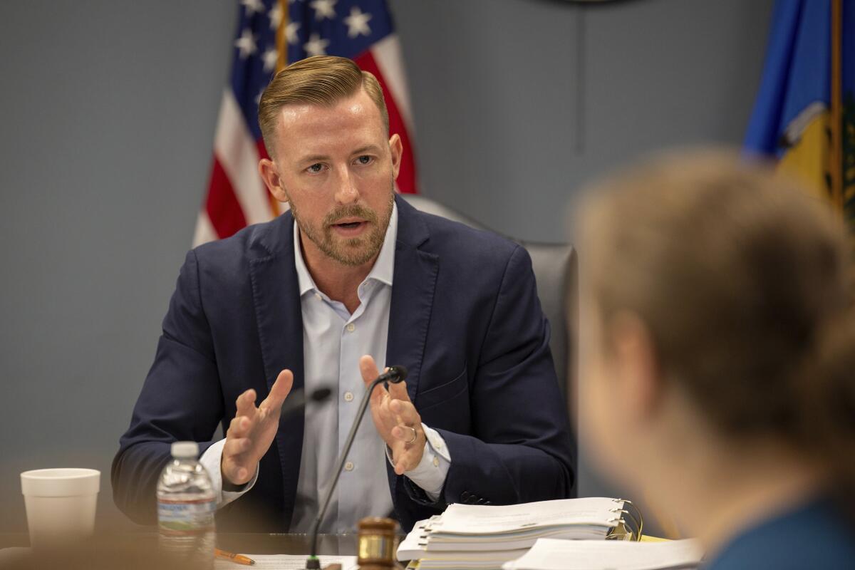 A man sits at a table with others and gestures while he speaks. 