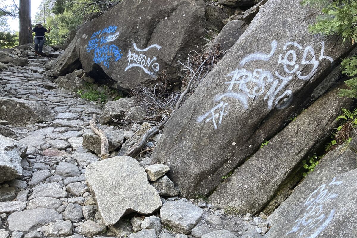 In this photo released, Sunday June 12, 2022, by the National Park Service, a hiker walks down a graffiti covered trail in Yosemite National Park, Calif. (National Park Service via AP)