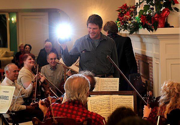 David Sandstrom snaps photos of musicians gathered to play Handel's "Messiah" at the home of William and Judy Sloan. Dozens of amateur and professional singers and instrumentalists gather each year for the festive event.