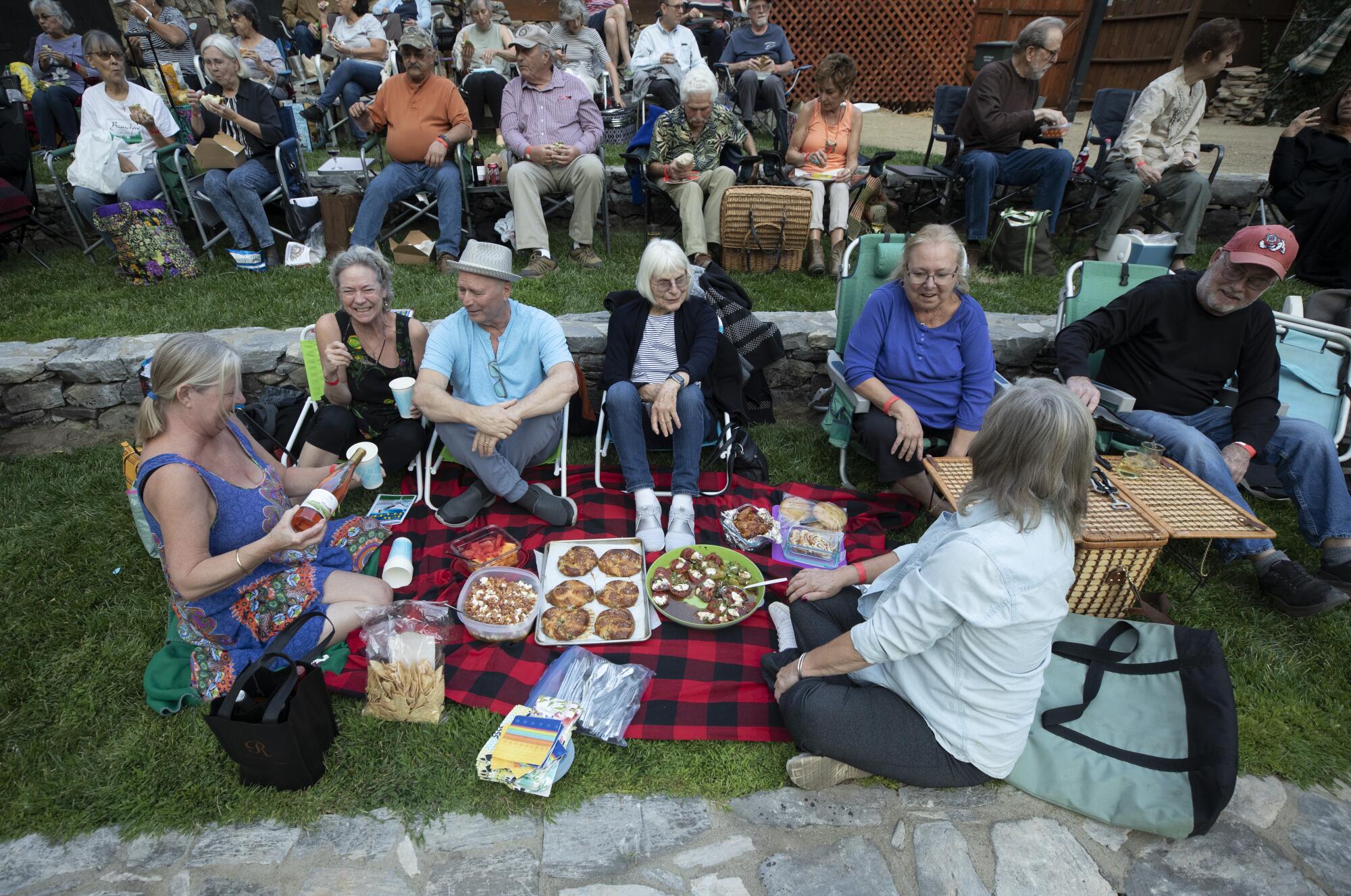 Playgoers sit around a picnic spread