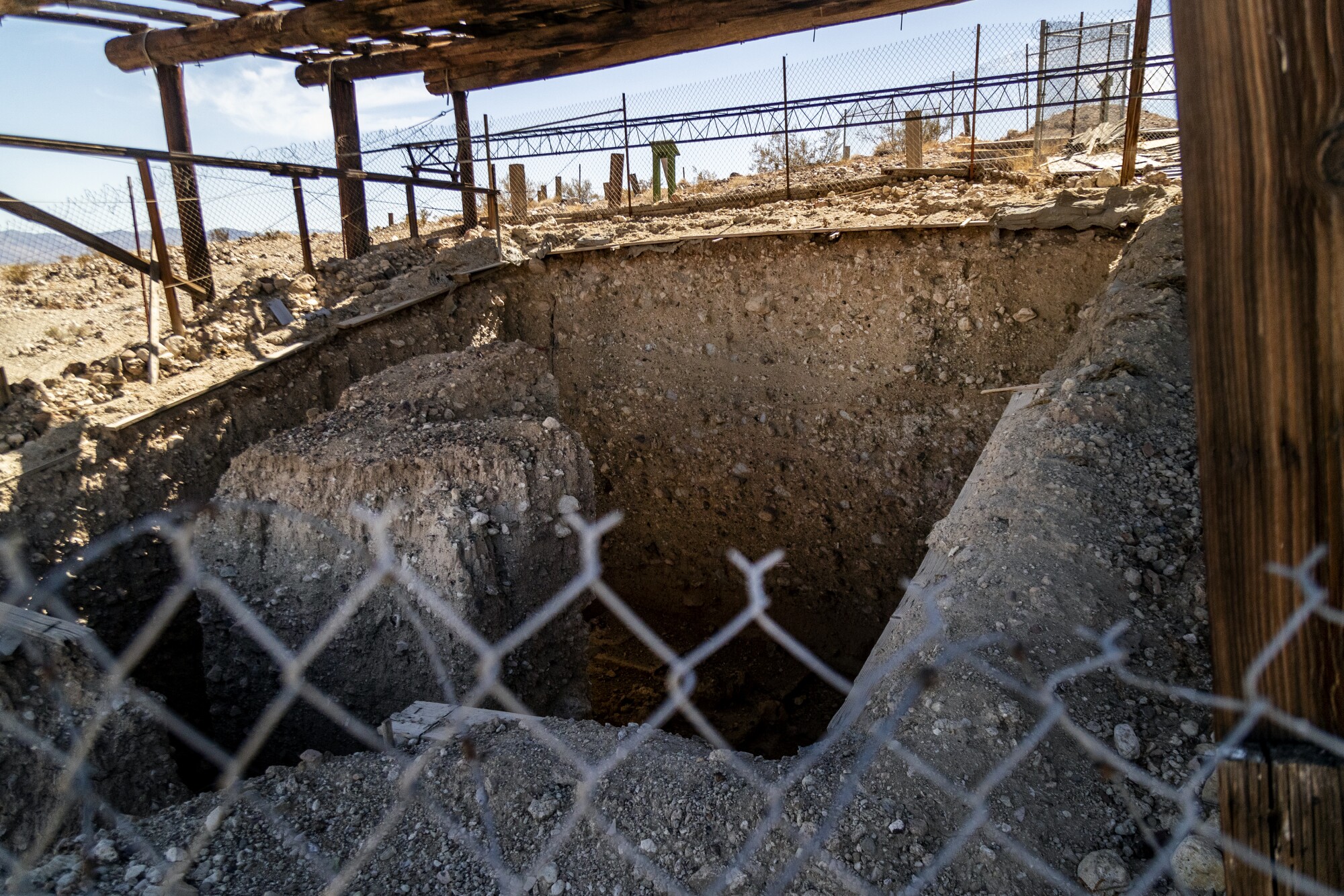 Chain-link fencing around a deep excavation pit in the dirt