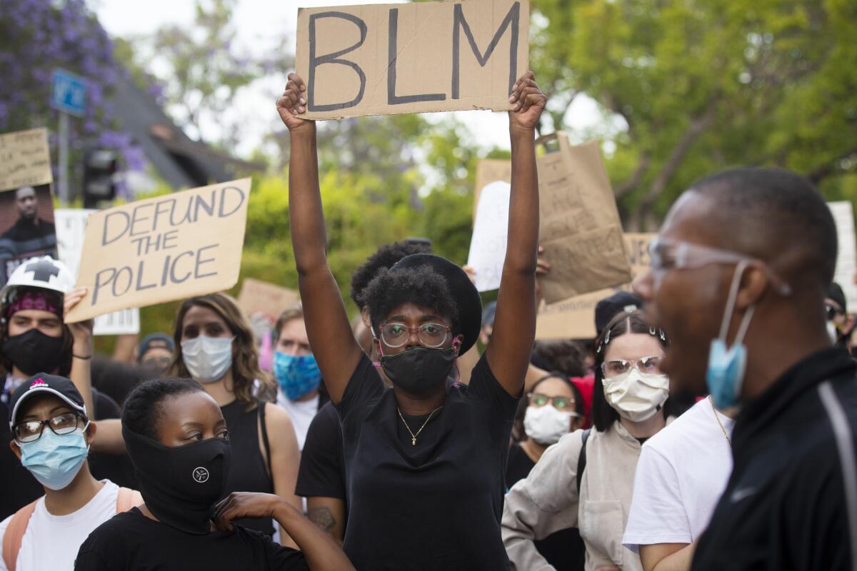 Protesters with cardboard signs that say Defund the Police and BLM