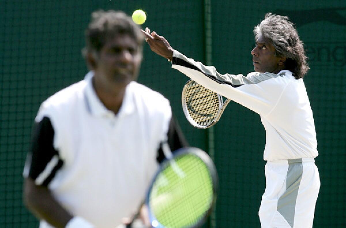 Anand Amritraj prepares to serves as his brother, Vijay, waits at the net during a Wimbledon doubles match.