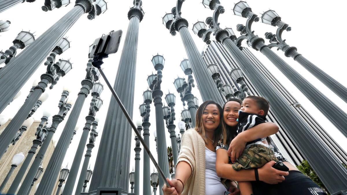 Marjorie Mabini takes a "selfie" with her niece Jaydah Mabini, and son Jaren, 1, in front of the "Urban Light" lampost installation at the Los Angeles County Museum of Art.