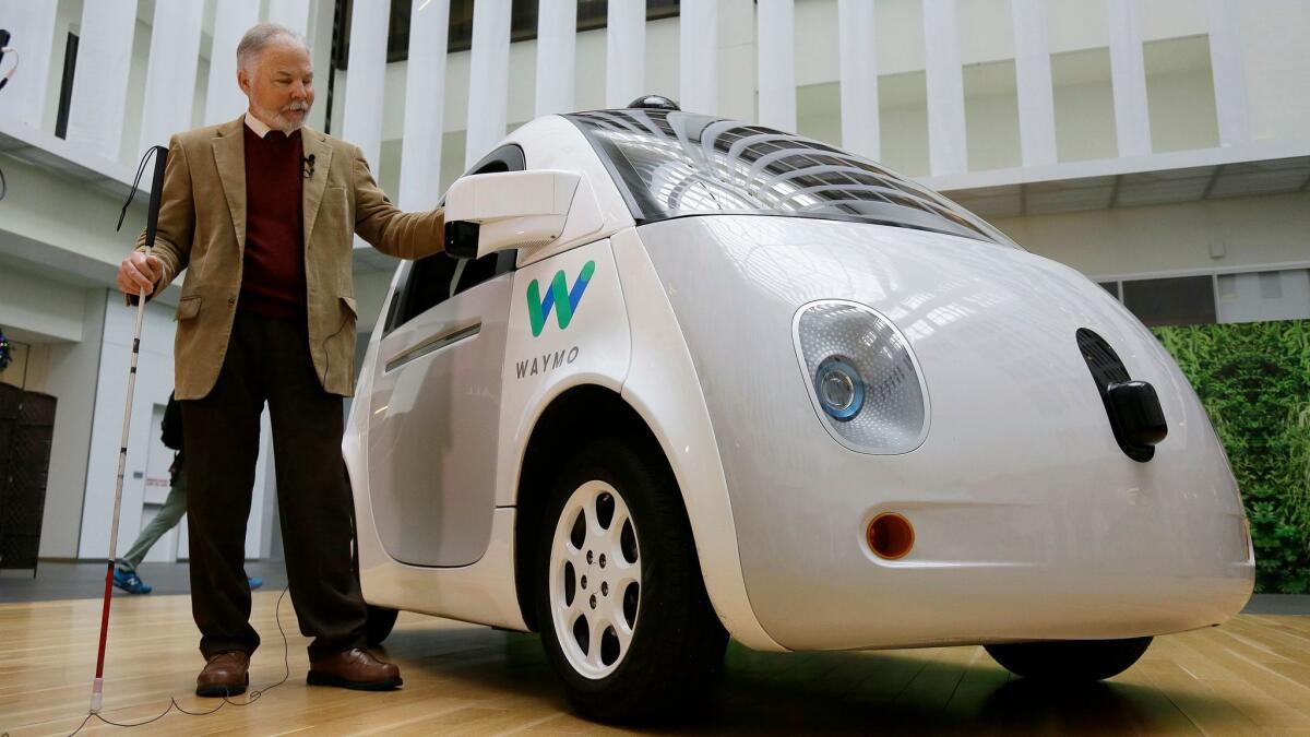 Steve Mahan, former director of the Santa Clara Valley Blind Center, stands beside a Waymo self-driving car Tuesday in San Francisco.