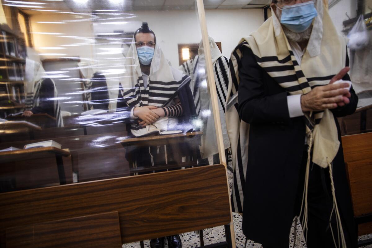 Ultra-Orthodox Jews pray in a synagogue separated by a plastic partition in Bnei Brak, Israel, on Friday.