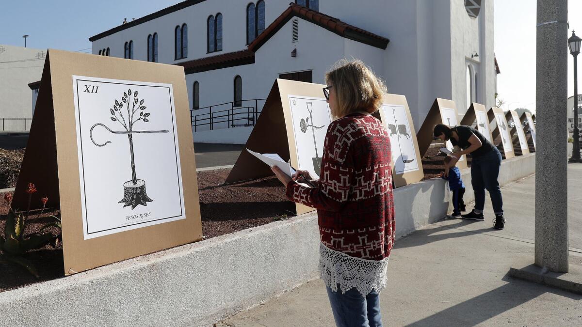 Charlene Ashendorf of Costa Mesa looks at a public art installation called "Stations in the Street" outside First United Methodist Church of Costa Mesa on Good Friday. Artist Scott Erickson created the representations of the Stations of the Cross.