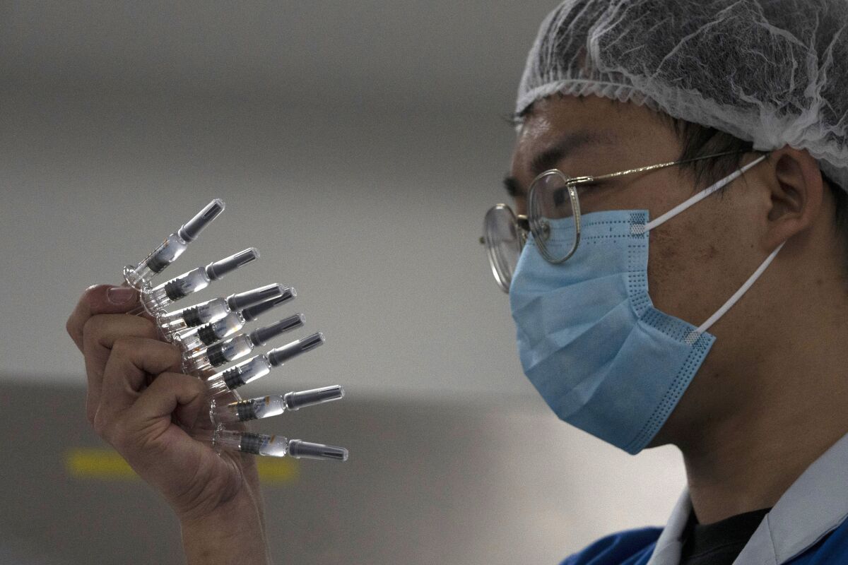 In this Sept. 24, 2020, file photo, an employee manually inspects syringes of the SARS CoV-2 Vaccine for COVID-19 produced by Sinovac at its factory in Beijing. China is rapidly increasing the number of people receiving its experimental coronavirus vaccines, with a city offering one to the general public and a biotech company providing another free to students going abroad. (AP Photo/Ng Han Guan, File)