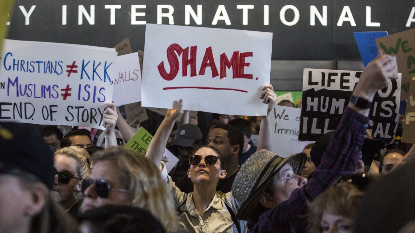 Meg Heatherly, 27, of Los Angeles holds a "Shame" sign during a protest at the Tom Bradley International Terminal at LAX on Jan. 29, 2017.