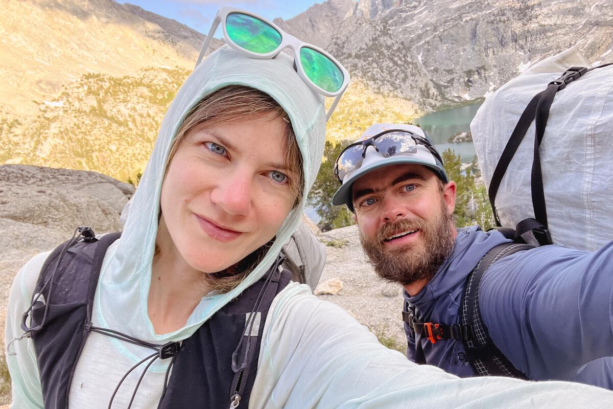 Bir kadın ve adam arka planda dağların olduğu bir selfie çekiyor. 