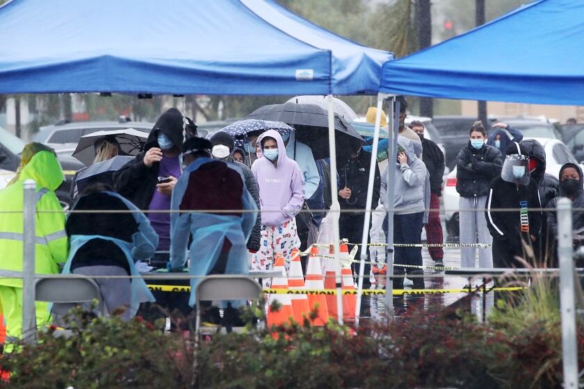 LONG BEACH, CA. - DEC 29, 2021. People line up in te rain for COVID-19 testing in the parking lot of Long Beach City College on Wednesday, Dec 29, 2021. (Luis Sinco / Los Angeles Times)