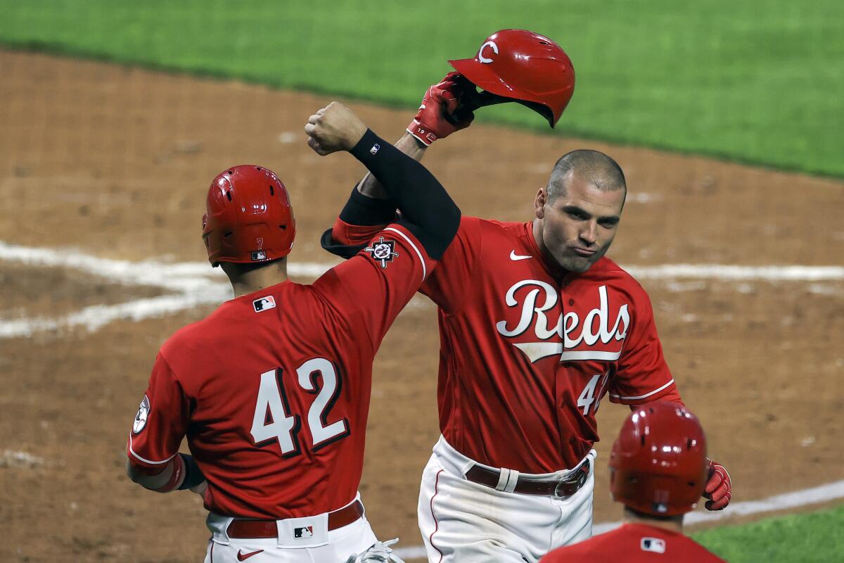 Cincinnati Reds' Eugenio Suarez, left, celebrates the two-run home run by Joey Votto, right, during the third inning of a baseball game against the Cleveland Indians in Cincinnati, Friday, April 16, 2021. (AP Photo/Aaron Doster)