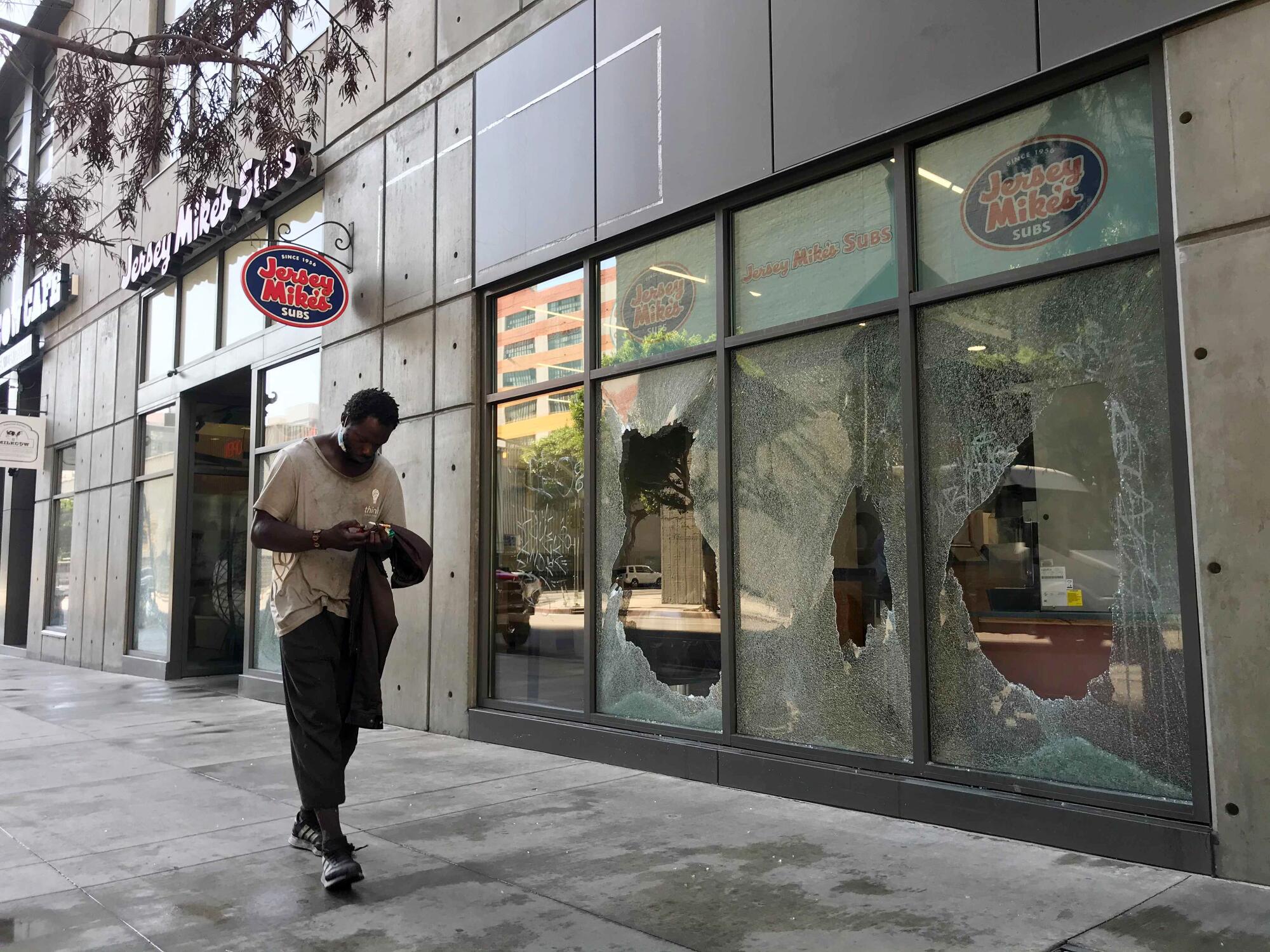 A man walks by broken windows at a Jersey Mike's near Staples Center after Sunday night's Lakers celebration.