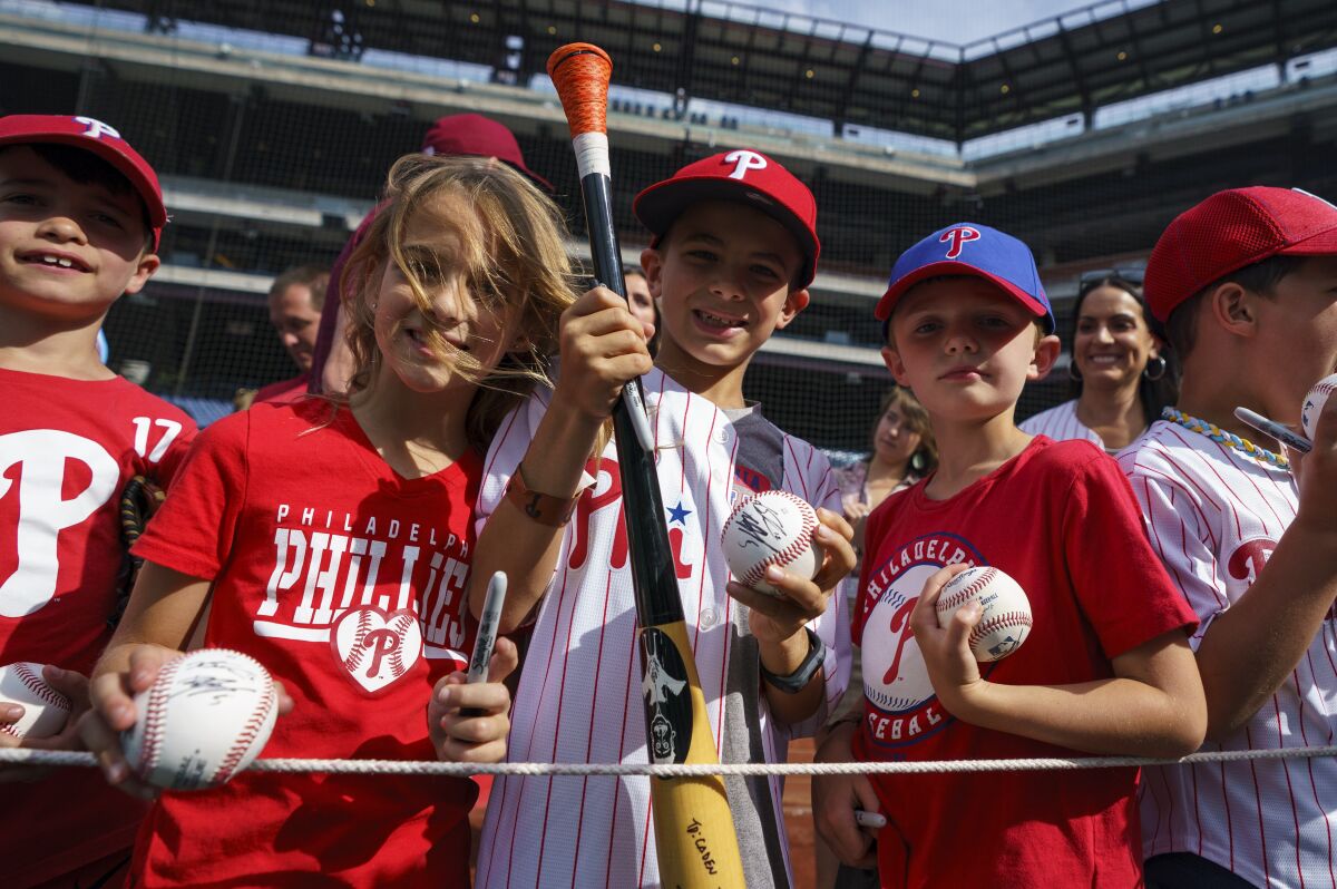West Chester's Caden Marge, center, holds up signed memorabilia that he received from Philadelphia Phillies' Bryson Stott during warmups prior to a baseball game against the Arizona Diamondbacks, Friday, June 10, 2022, in Philadelphia. (AP Photo/Chris Szagola)