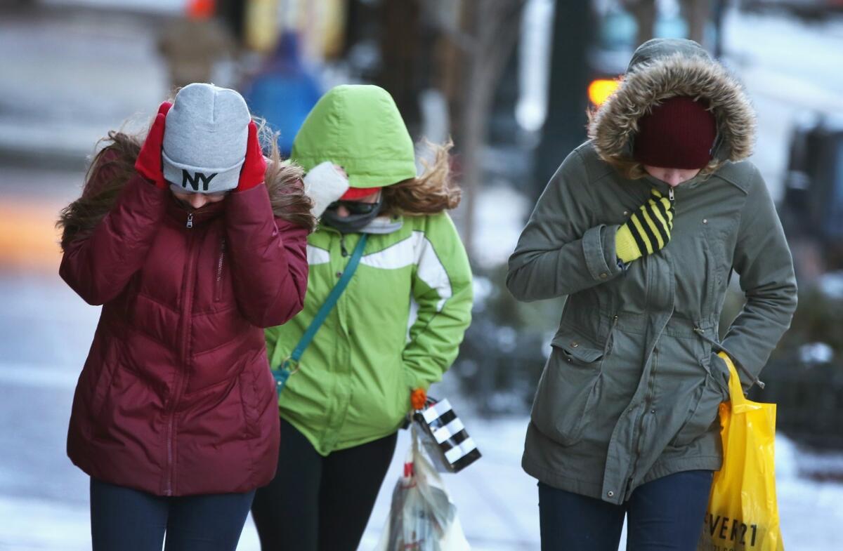 Pedestrians try to keep warm as they walk through downtown Chicago in below-zero temperatures.