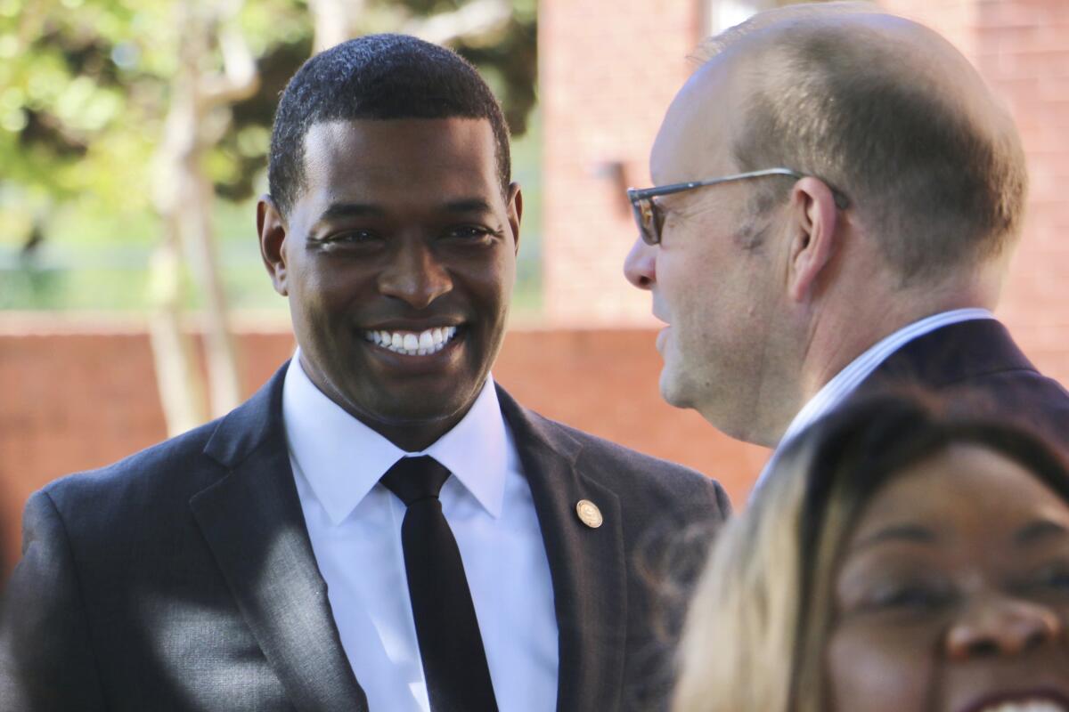 Two men in business suits, pictured from the shoulders up, greeting each other