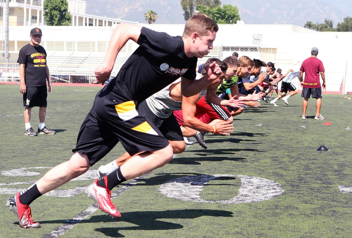 This May 2014 photo shows members of the La Cañada High School football team during a spring practice. Work to replace the artificial turf on the field will take place throughout June and July, with a target date to open between July 18 and 20 in time for football activities.