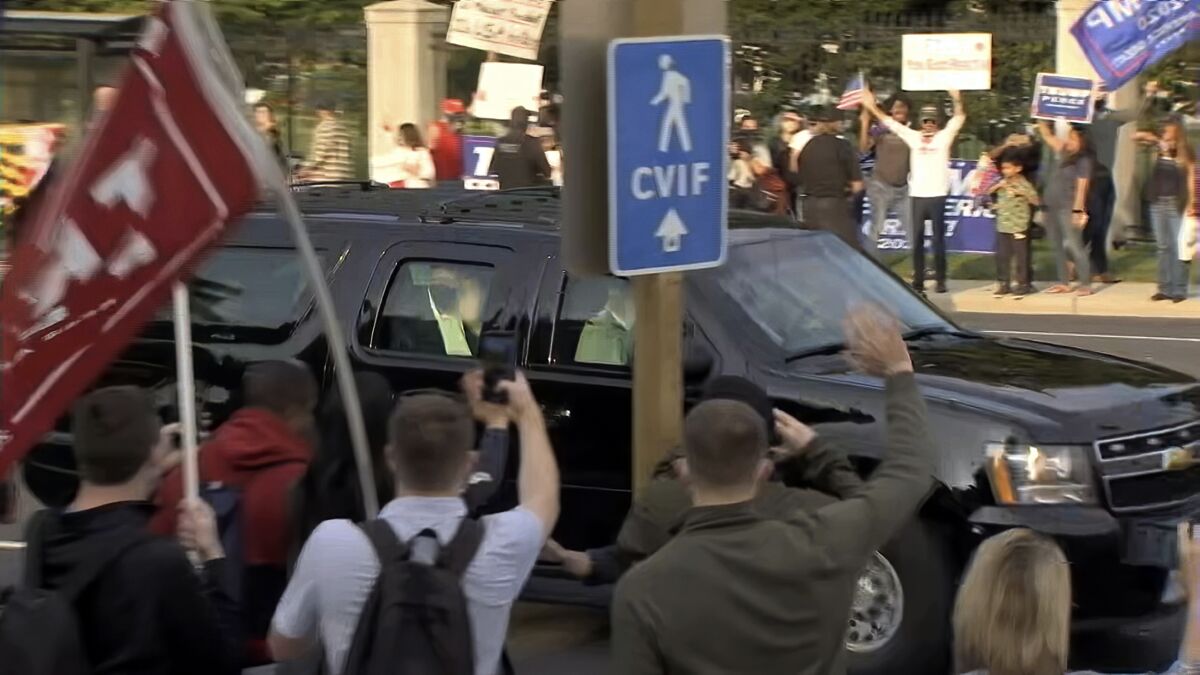 President Trump waves from the back of a car in a motorcade