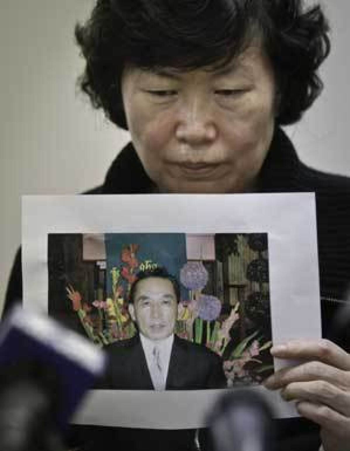 Serim Han holds a picture of her husband, Ki-Suck Han, who was killed by a train after being pushed onto the subway tracks.