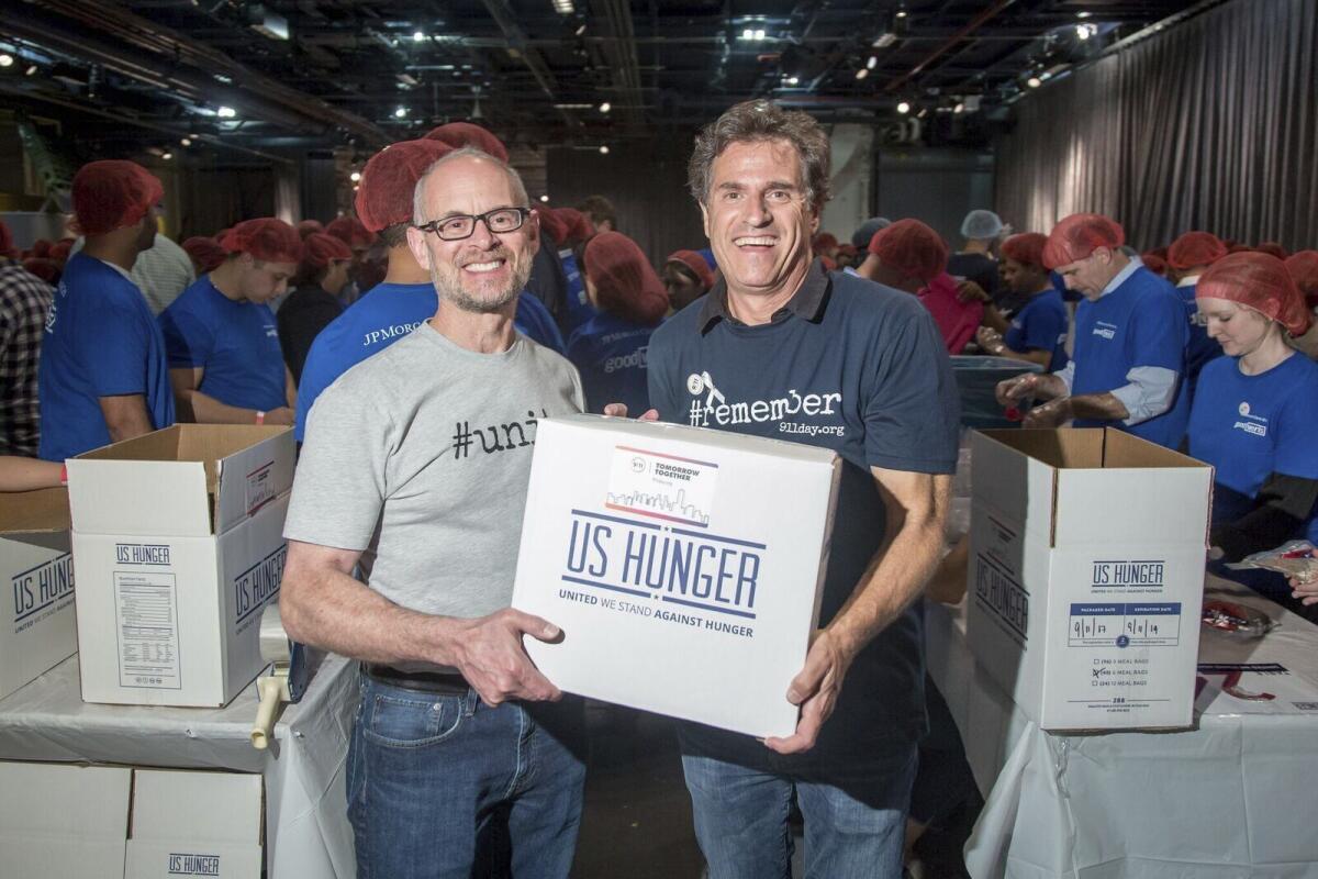 In this Sept. 11, 2017 photo, 9/11 Day co-founders Jay Winuk, left, and David Paine pack meals for food bank distribution on Sept. 11, 2017 at the Intrepid Sea, Air and Space Museum in New York. To mark the 20th anniversary of the terrorist attacks that killed thousands, including Winuk’s younger brother, Glenn, the 9/11 Day co-founders are expanding their efforts with a CNN special “Shine a Light” airing on Saturday, Sept. 11, 2021. (9/11 Day via AP)