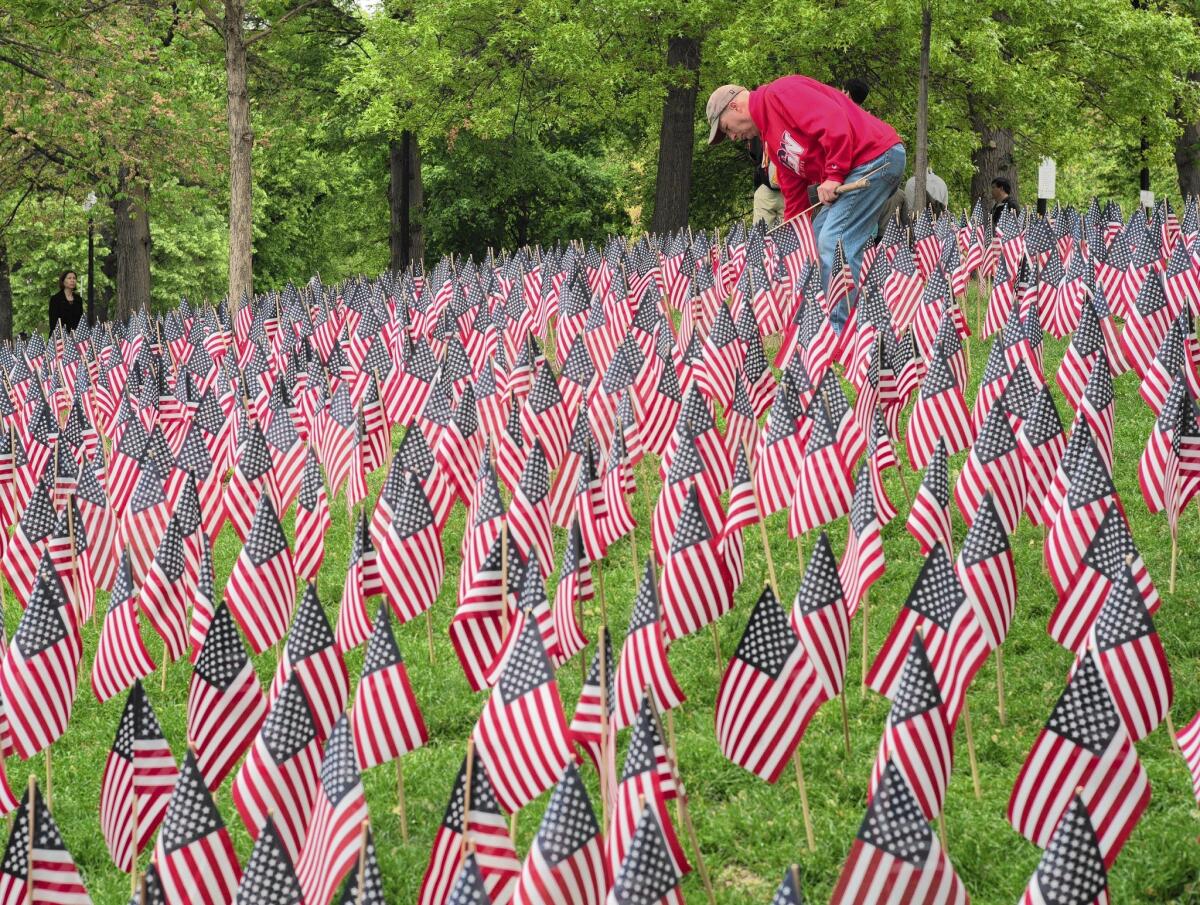 A volunteer tends to the garden of 37,000 flags representing each Massachusetts soldier lost since the Revolutionary War on display on the Boston Common in advance of Memorial Day.
