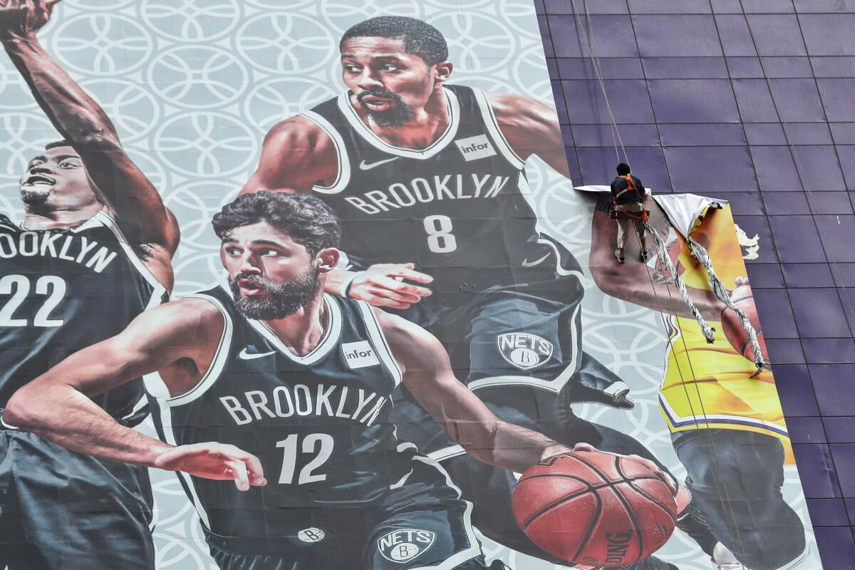 Worker in Shanghai removes a banner advertising Lakers-Nets game