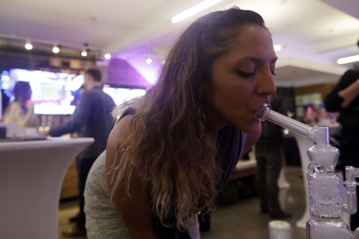 Krystal Xiques smokes marijuana at a rally in support of Proposition 64 at Sparc Dispensary on Tuesday in San Francisco.