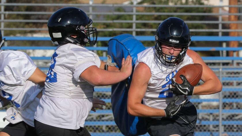 Ramona’s Sean McDonald does his best to corral a handoff in the Bulldogs’ first practice of the season.