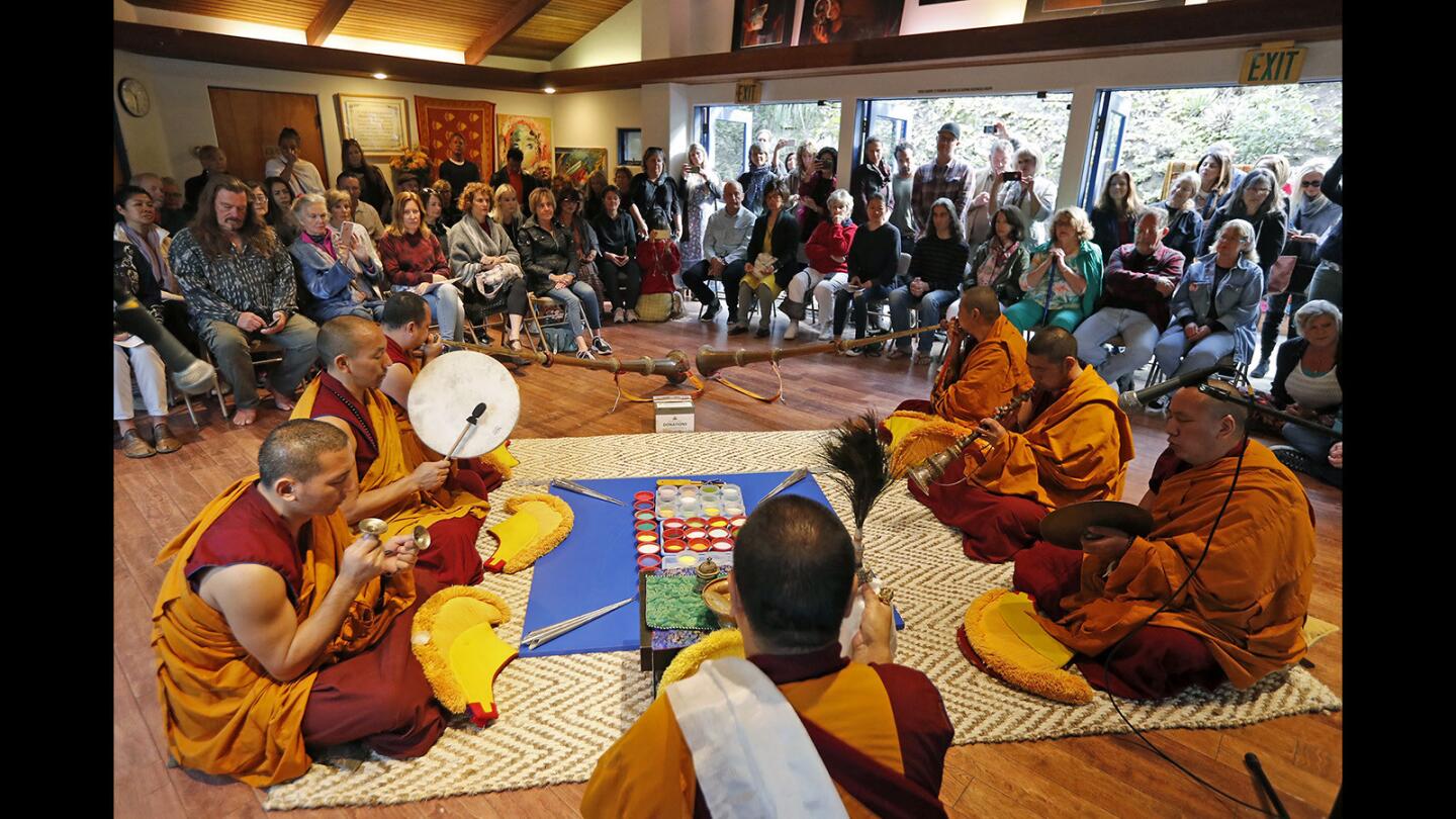 Tibetan monks perform with traditional instruments during an opening ceremony for the creation of the White Tara mandala at the Sawdust Art & Craft Festival grounds in Laguna Beach on Monday. A mandala is an intricately designed geometric figure made from different colors of marble sand.